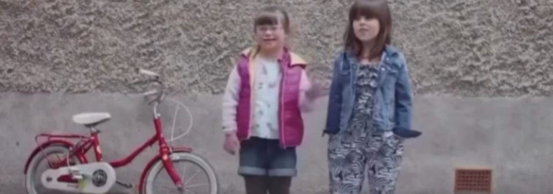 Afbeelding uit de video met twee kinderen en een fiets en de tekst: "And they're different!"