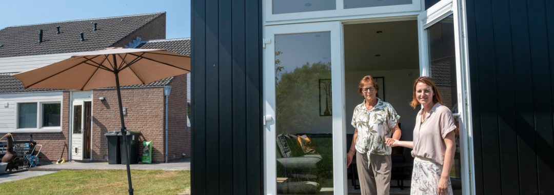 Moeder en dochter voor de deur van een mantelzorgwoning achter in de tuin van het huis