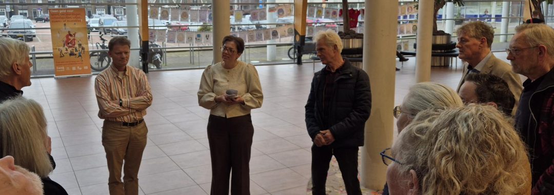 inwoners bieden in de hal van het gemeentehuis rapport aan aan de wethouder