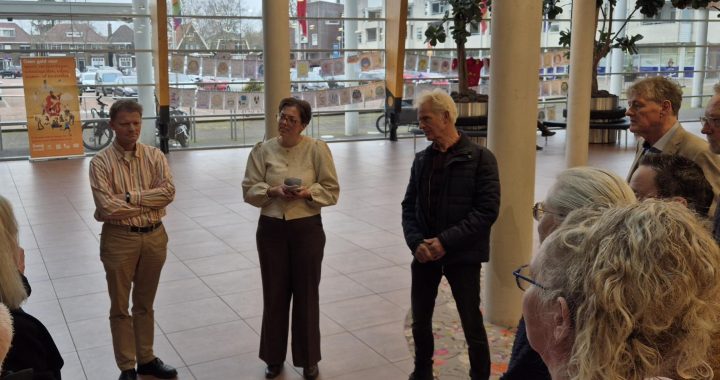 inwoners bieden in de hal van het gemeentehuis rapport aan aan de wethouder